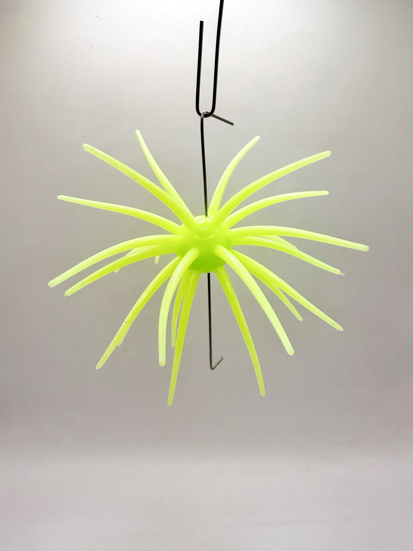 Neon yellow urchin lure on a plain background